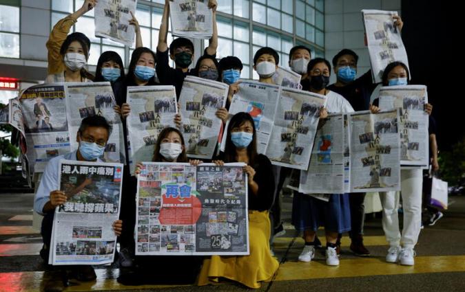 Staff members of Apple Daily and its publisher Next Digital pose with the final edition of Apple Daily at its headquarters in Hong Kong, China June 24, 2021. REUTERS/Tyrone Siu