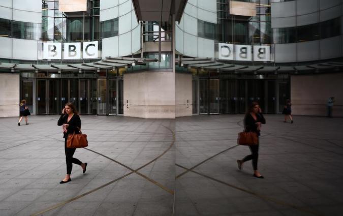 A woman is reflected as she passes the BBC's Broadcasting House in London, Britain July 19, 2017. REUTERS/Neil Hall