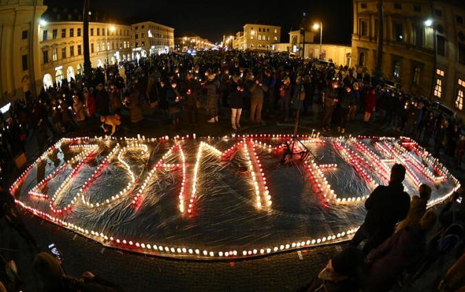 People light candles in the shape of a sign which reads "Solidarity" in protest against coronavirus disease (COVID-19) deniers at Odeonsplatz in Munich, Germany February 10, 2022. Picture taken with a a fish-eye lens. REUTERS/Lukas Barth
