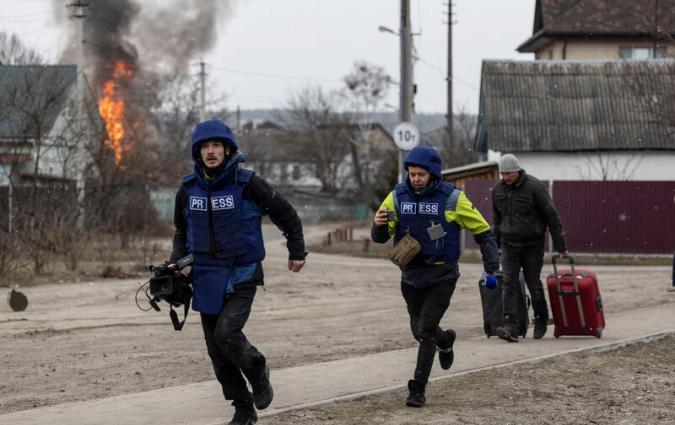 Journalists run for cover after heavy shelling on the only escape route used by locals, while Russian troops advance towards the capital, in Irpin, near Kyiv, Ukraine March 6, 2022. REUTERS/Carlos Barria