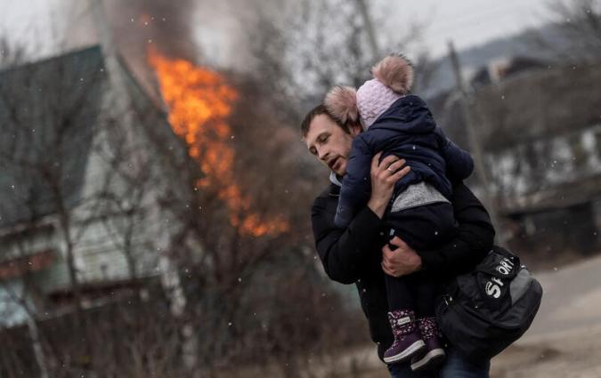 A man and a child escape from the town of Irpin, after heavy shelling on the only escape route used by locals, while Russian troops advance towards the capital of Kyiv, in Irpin, near Kyiv, Ukraine March 6, 2022. REUTERS/Carlos Barria