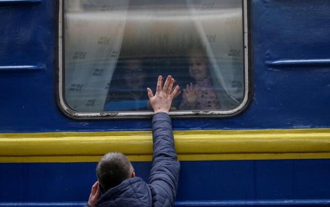 Children look out from an evacuation train from Kyiv to Lviv as they say goodbye to their father at Kyiv central train station in central Kyiv, Ukraine March 3, 2022. REUTERS/Gleb Garanich