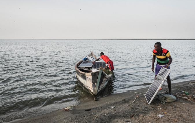 Two men load solar panels on a boat in Turkana County, Kenya. Credit: Maurizio Di Pietro / Climate Visuals Countdown