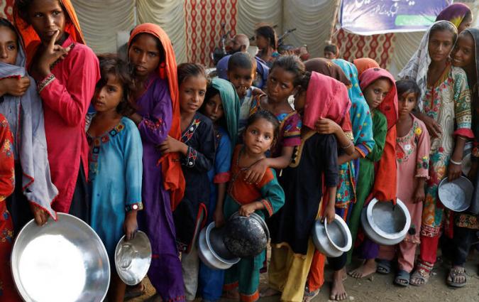 Flood victims gather to receive food handout in a camp, following rains and floods during the monsoon season in Sehwan, Pakistan September 14, 2022. REUTERS/Akhtar Soomro