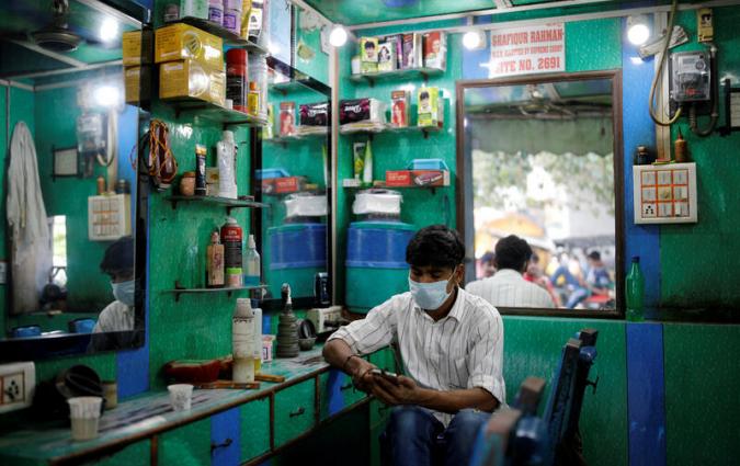 A barber looks at his phone, Delhi. India. REUTERS/Adnan Abidi