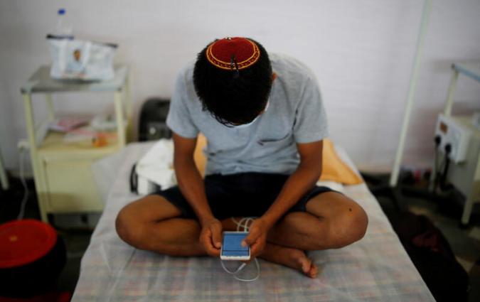An Indian checks his mobile phone at a COVID-19 care facility in New Delhi. REUTERS/Adnan Abidi 