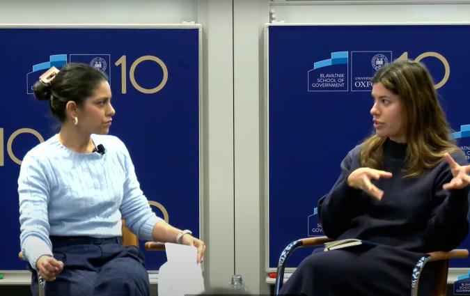 Mitali Mukherjee and Jane Bradley sit on the stage, looking at one another and speaking.