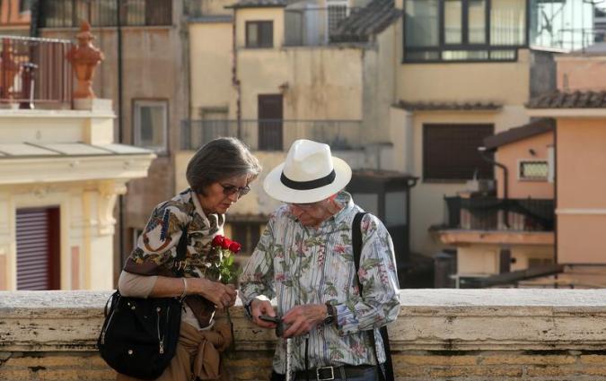 Elderly people look a mobile phone in downtown Rome.