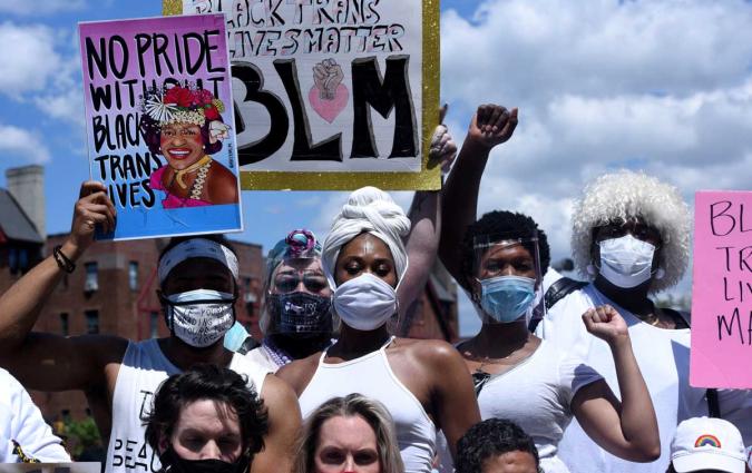 A gathering of five people wearing masks and holding signs that read "No pride without Black trans lives" REUTERS/Stephanie Keith