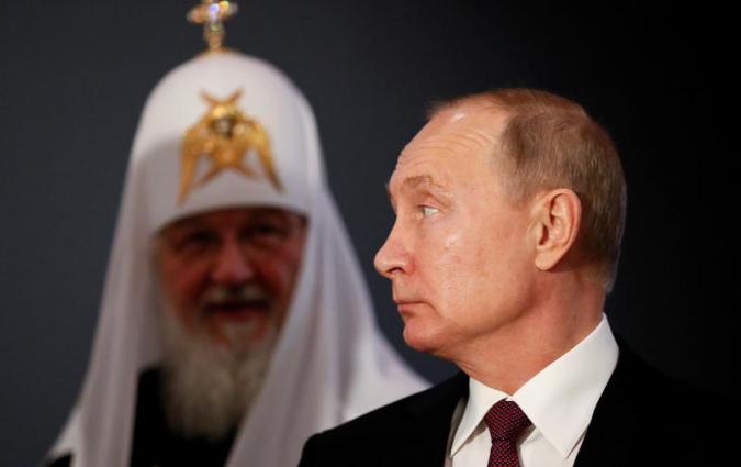Putin looks over his shoulder at Patriarch Kirill in full regalia. 