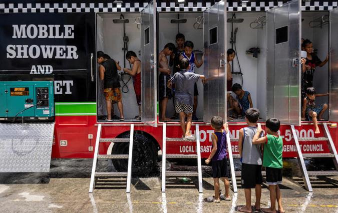 Children use a mobile shower provided by the local government, amid extreme heat in Valenzuela, Metro Manila, Philippines, May 2, 2024. REUTERS/Eloisa Lopez TPX IMAGES OF THE DAY
