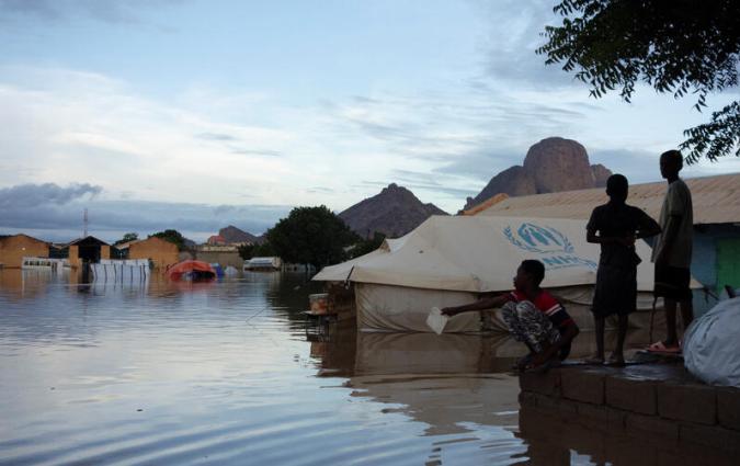 Displaced Sudanese people next to floodwater