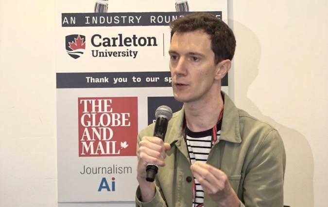 Florent Daudens speaks holding a microphone and gesticulating in front of a sign displaying the logos of several news and AI organisations.