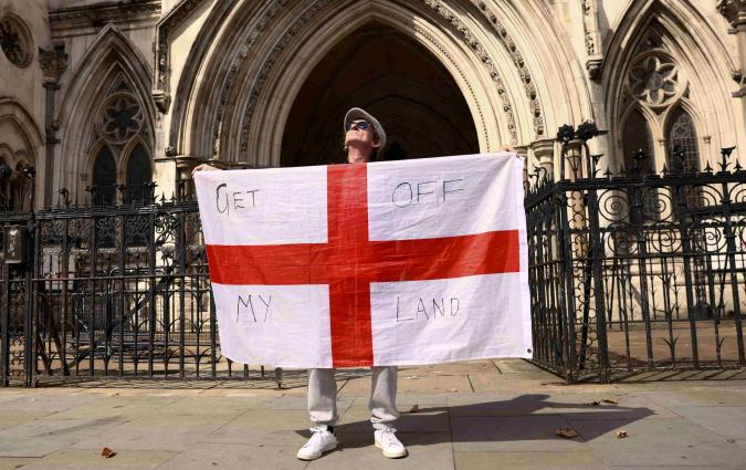 A protester holds up England's St George's flag outside the Royal Courts of Justice in London.