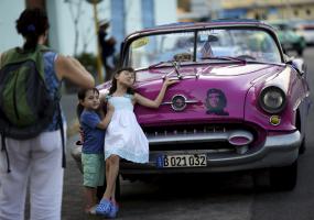 American tourists pose for a photo by an old car in Havana, Cuba