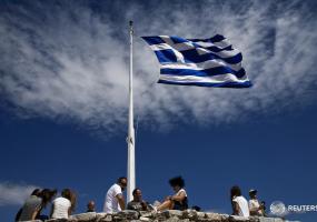 people sitting under the greek flag