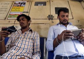 Commuters watch videos on their mobile phones as they travel in a suburban train in Mumbai, India (photograph: Shailesh Andrade)