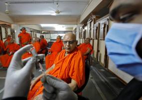 A Hindu saint watches a healthcare worker fill a syringe with a COVID-19 vaccine in Ahmedabad, India. REUTERS/Amit Dave