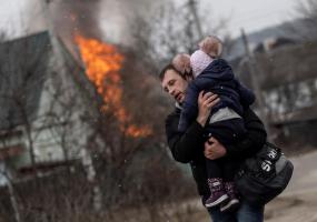 A man and a child escape from the town of Irpin, after heavy shelling on the only escape route used by locals, while Russian troops advance towards the capital of Kyiv, in Irpin, near Kyiv, Ukraine March 6, 2022. REUTERS/Carlos Barria