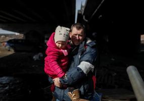 People cross the Irpin river under a destroyed bridge as they evacuate from Irpin town, amid Russia's invasion of Ukraine, outside of Kyiv, Ukraine March 12, 2022. REUTERS/Gleb Garanich
