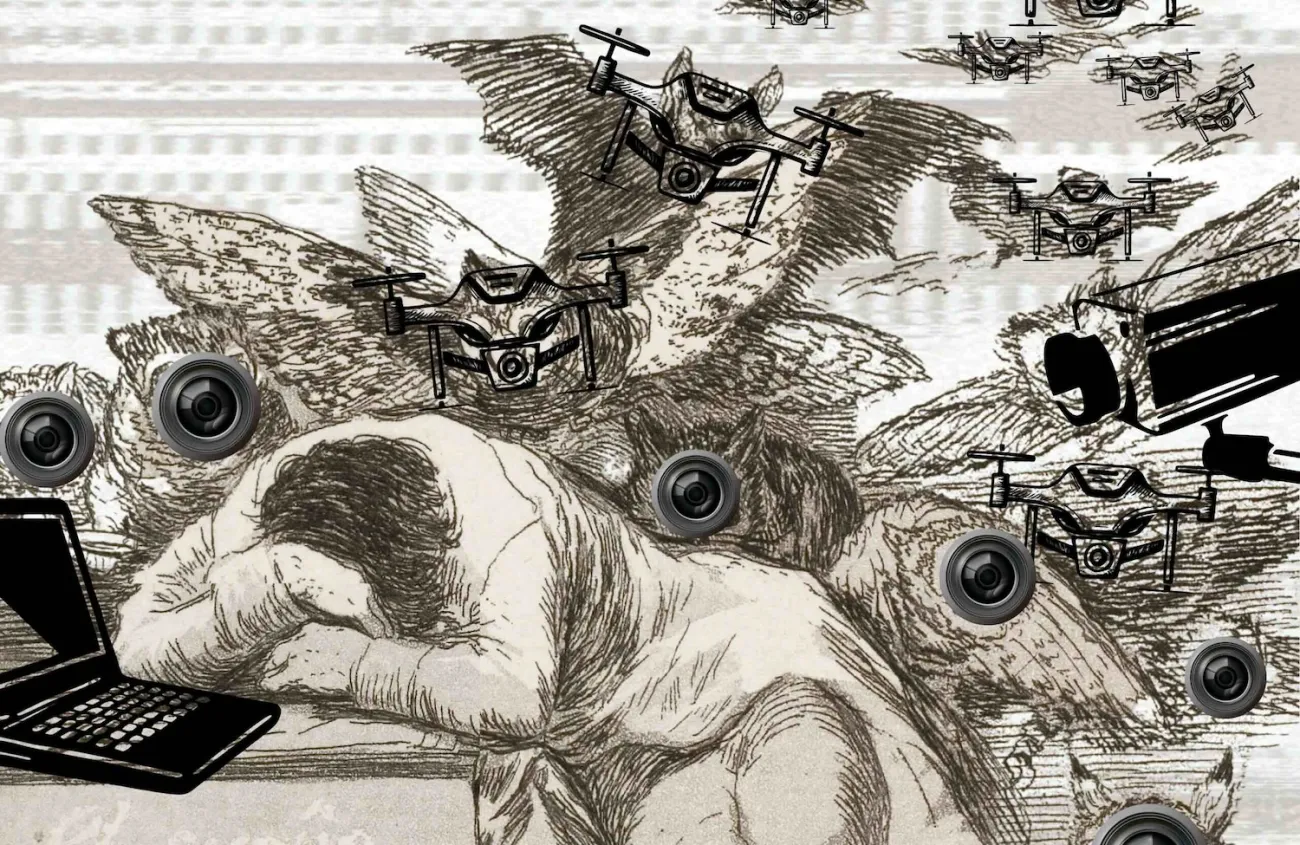 A digital collage based on Goya’s etching showing a person asleep at a desk. The figure leans forward with their head on their arms. Around them hover many small drones and large video surveillance cameras, replacing the original owls and bats. A laptop sits open on the desk. Faint text on the desk reads “The sleep of reason produces monsters.” A label over the word “reason” says “AUTONOM-IA.” The overall effect suggests technology watching and controlling a passive person